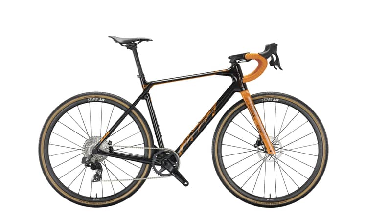 Road bike in matte black with orange accents, carbon frame, drop handlebars, disc brakes, and gravel tires.